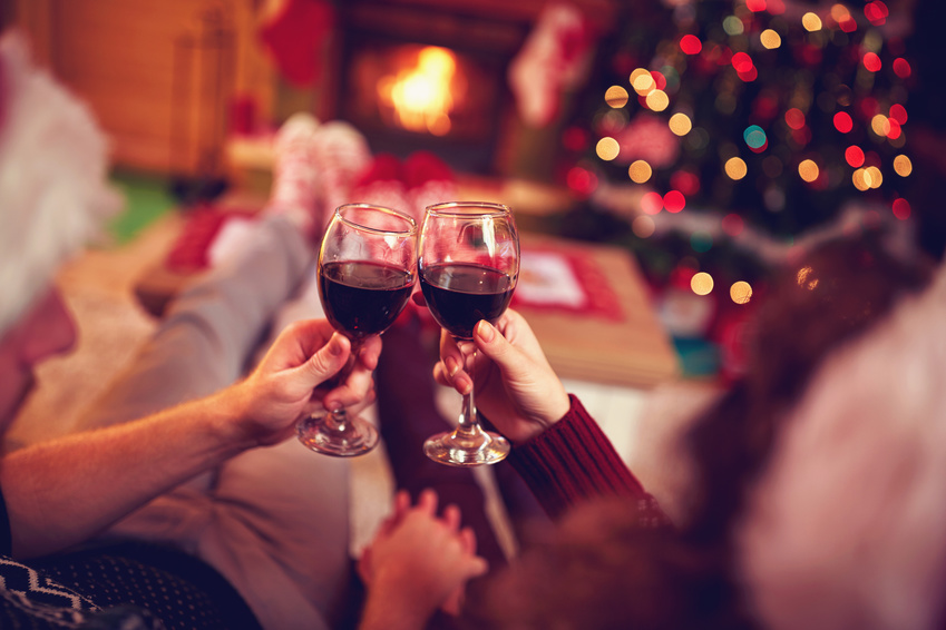 romantic couple with red wine, against xmas tree and fireplace